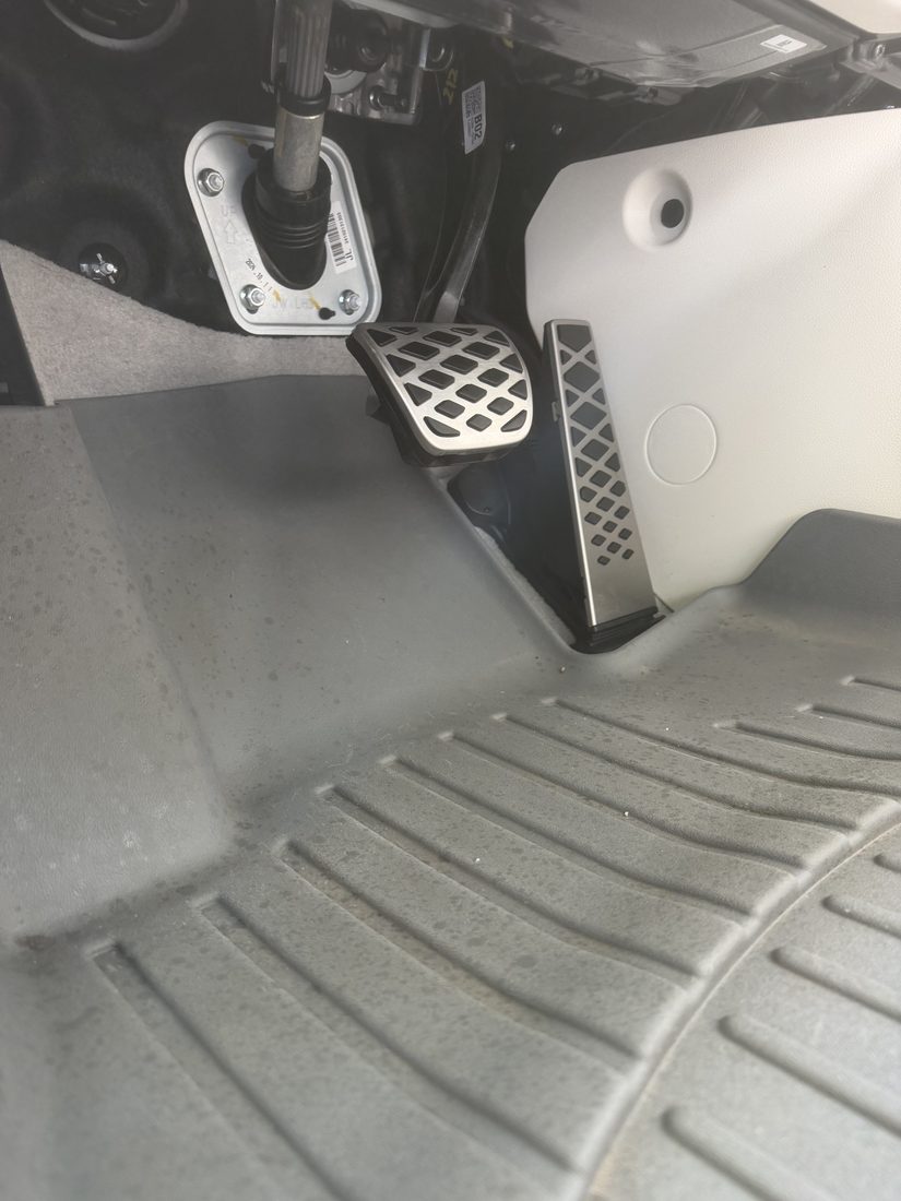 The same driver footwell after detailing — mat and pedal area completely clean