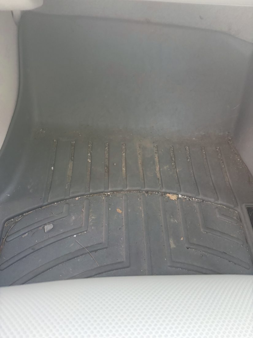 Passenger floor mat before detailing — caked in dried dirt and grit