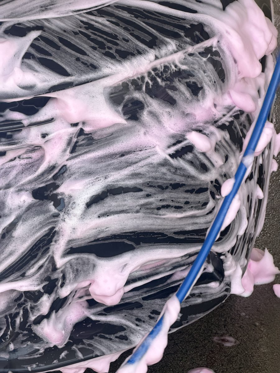 Thick wash foam sheeting down the dark paint of a Dodge Charger